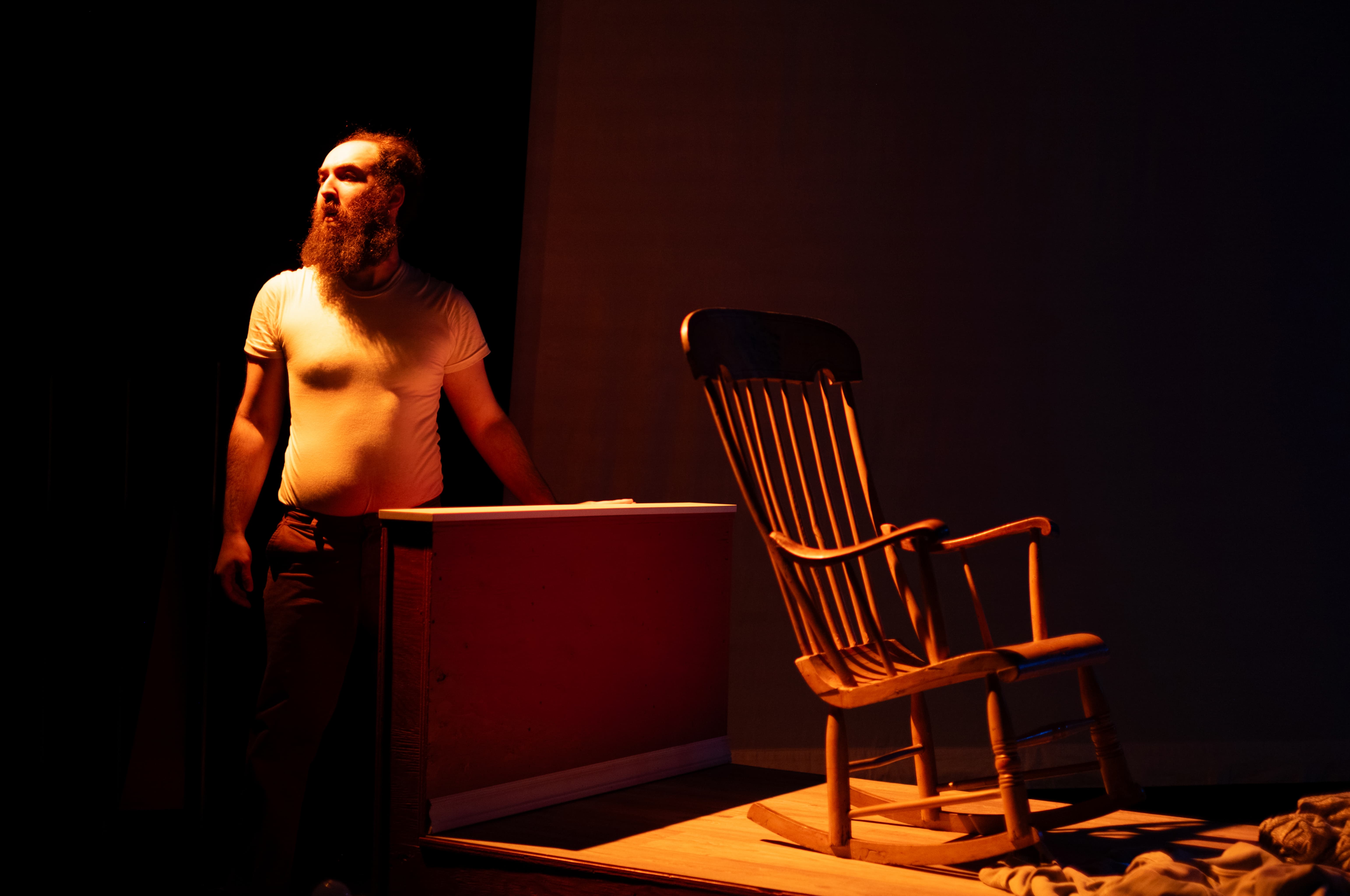 Actor Hayden Finkelshtain in a theater scenario. Rocking chair on the side 