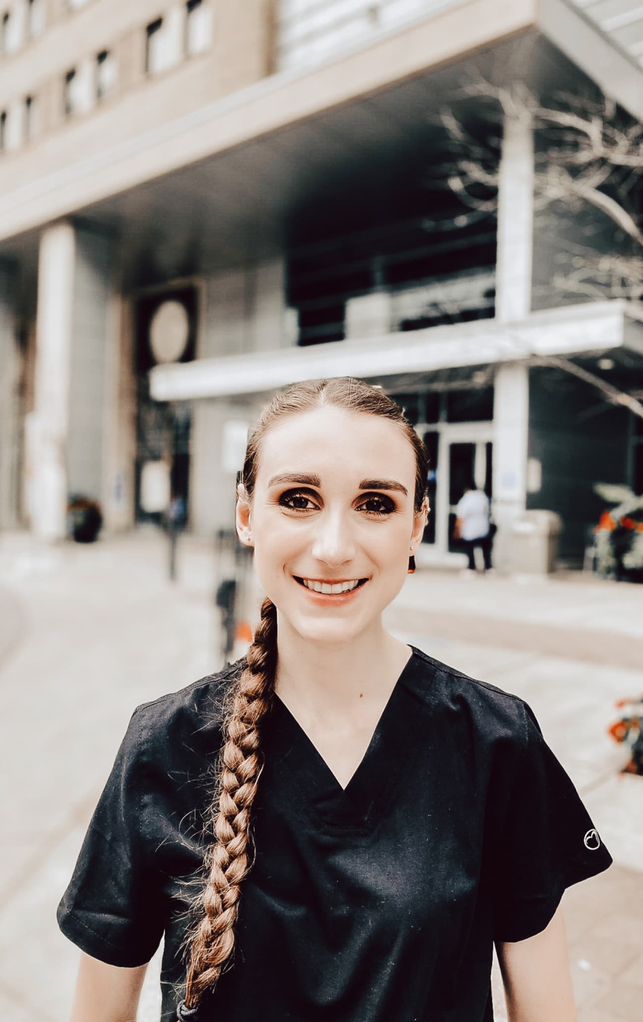 Autumn Rennie wearing dark scrubs in front of a building 